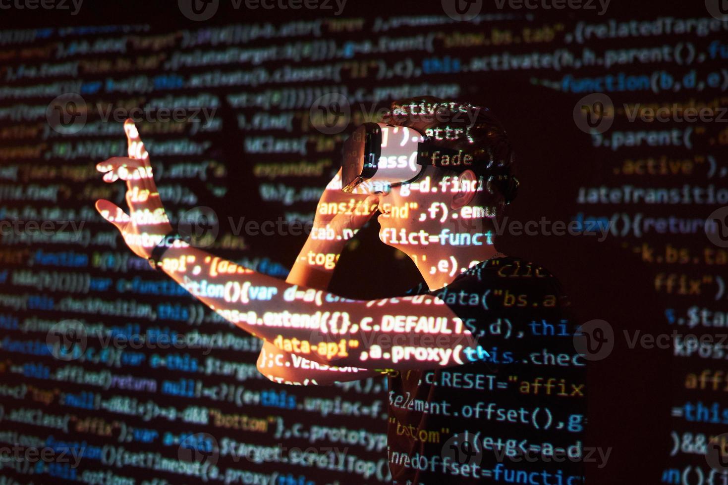 Double exposure of a caucasian man and Virtual reality headset is presumably a gamer or a hacker cracking the code into a secure network or server, with lines of code photo