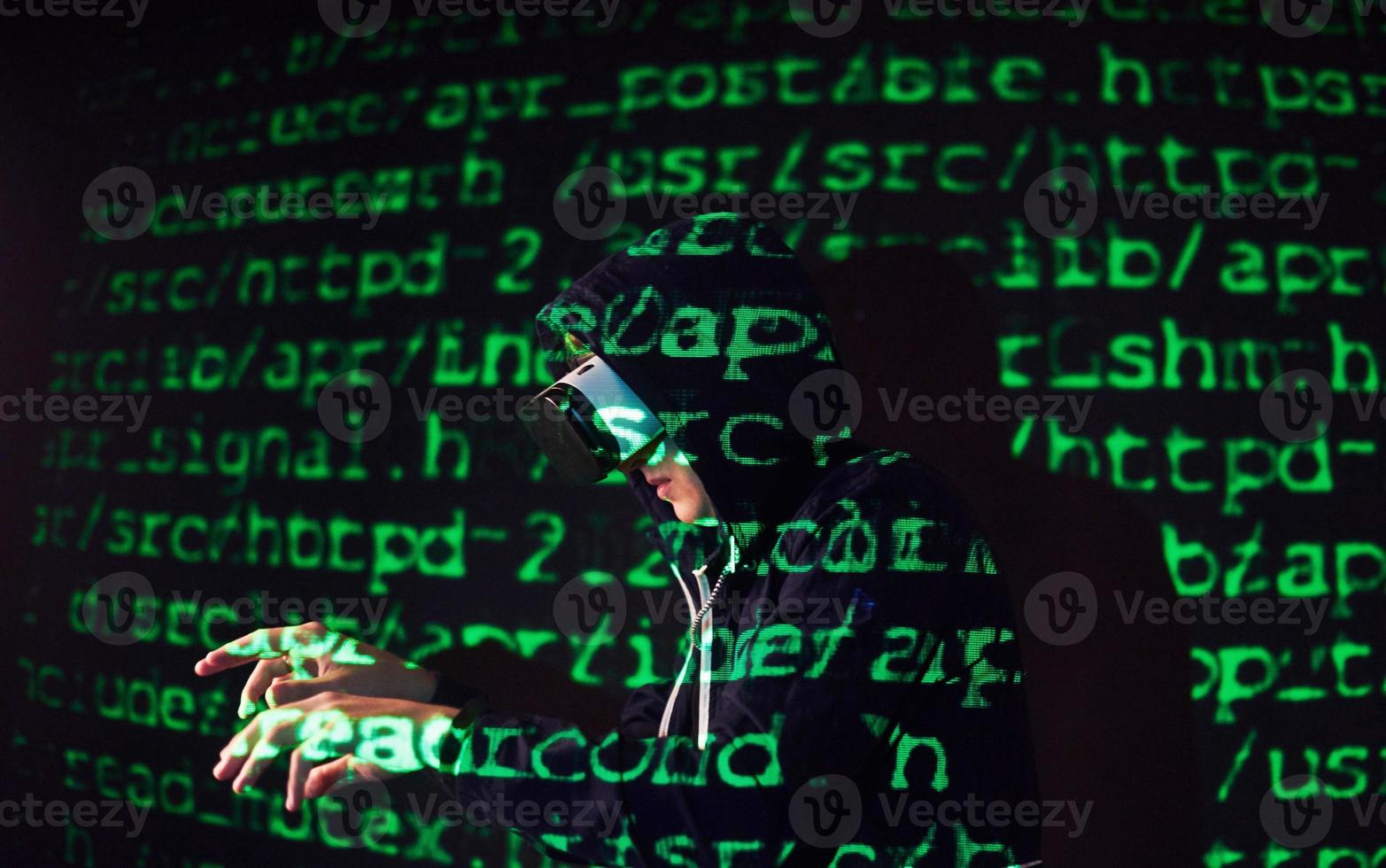 Double exposure of a caucasian man and Virtual reality headset is presumably a gamer or a hacker cracking the code into a secure network or server, with lines of code photo
