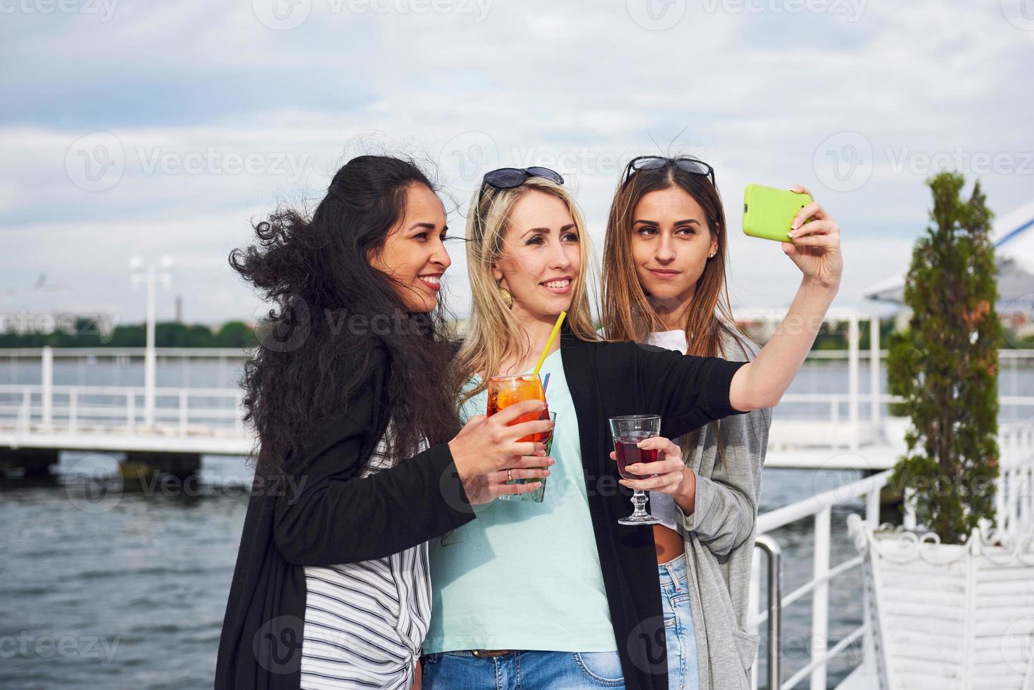 hermosas chicas sonrientes hacen selfie cerca del agua. emociones positivas. foto