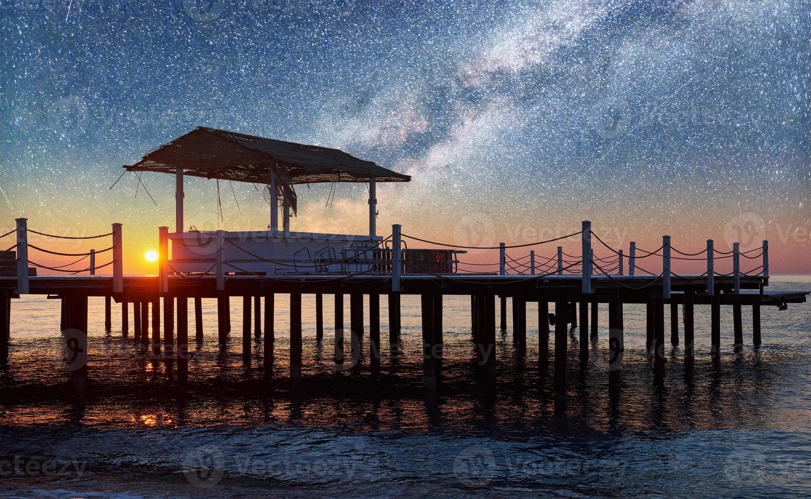 Beautiful view of wooden pier in the sea and starry sky and the Milky Way. photo