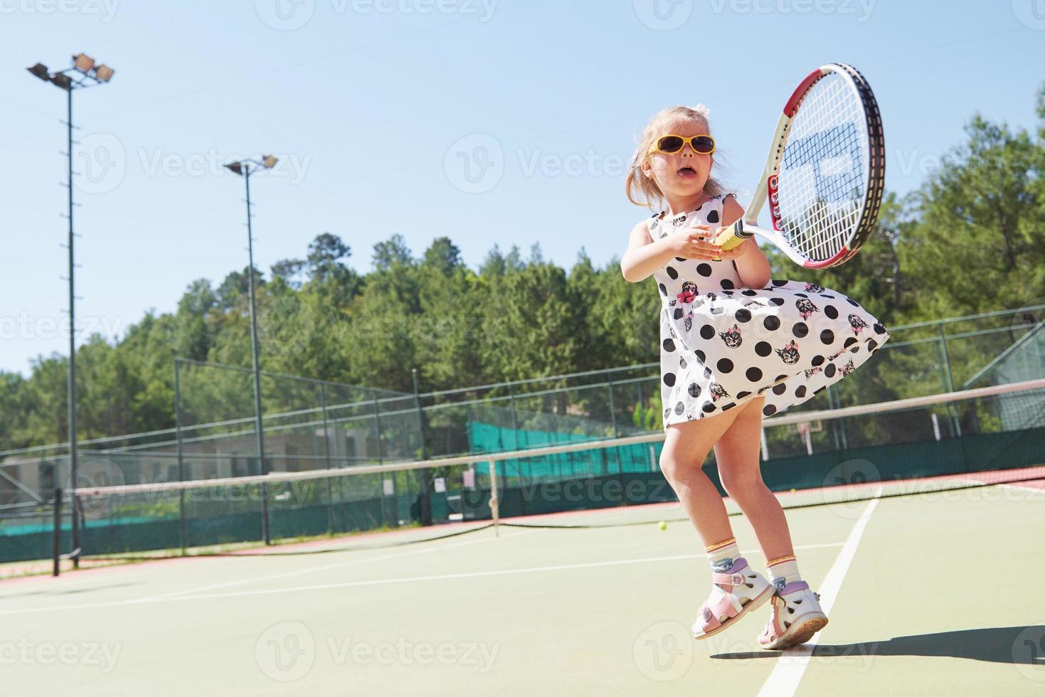 Happy little girl playing tennis photo