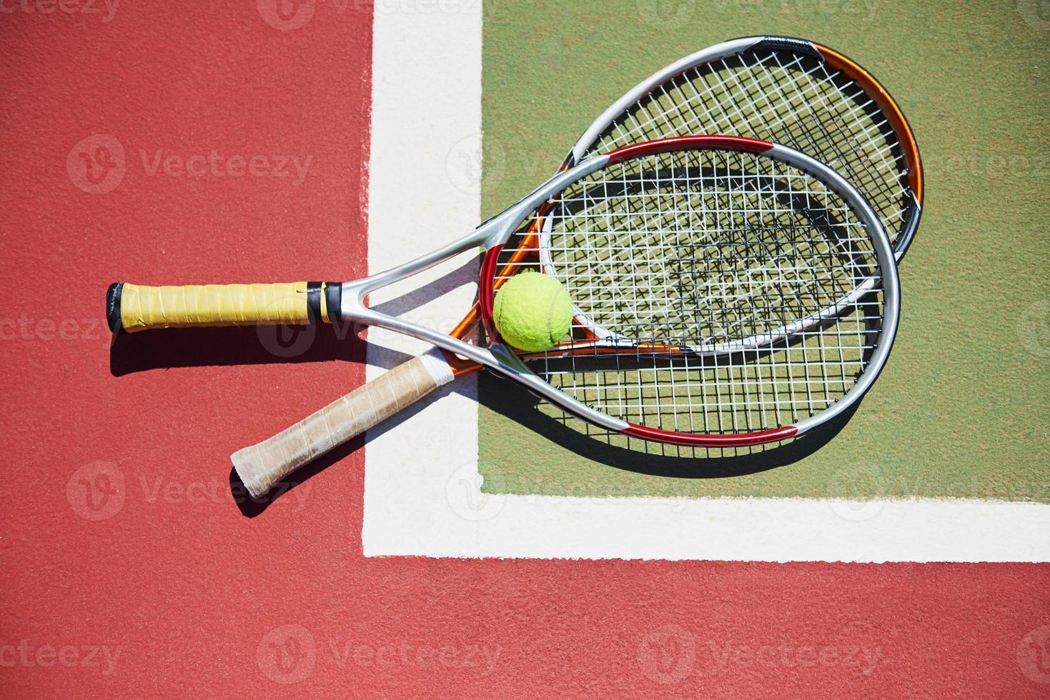 una raqueta de tenis y una pelota de tenis nueva en una cancha de tenis recién pintada foto