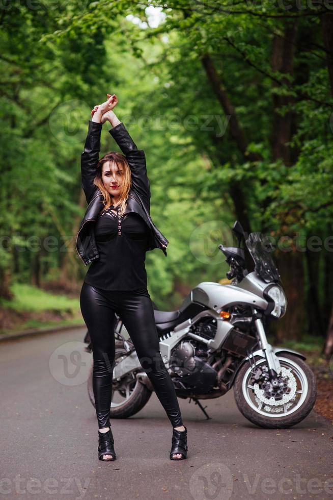 una atractiva chica sexy en una moto deportiva posando afuera foto