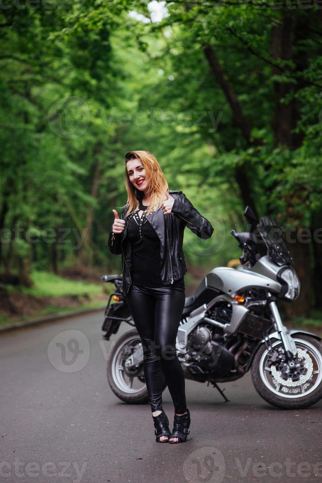 An attractive sexy girl on a sports motorbike posing outside photo