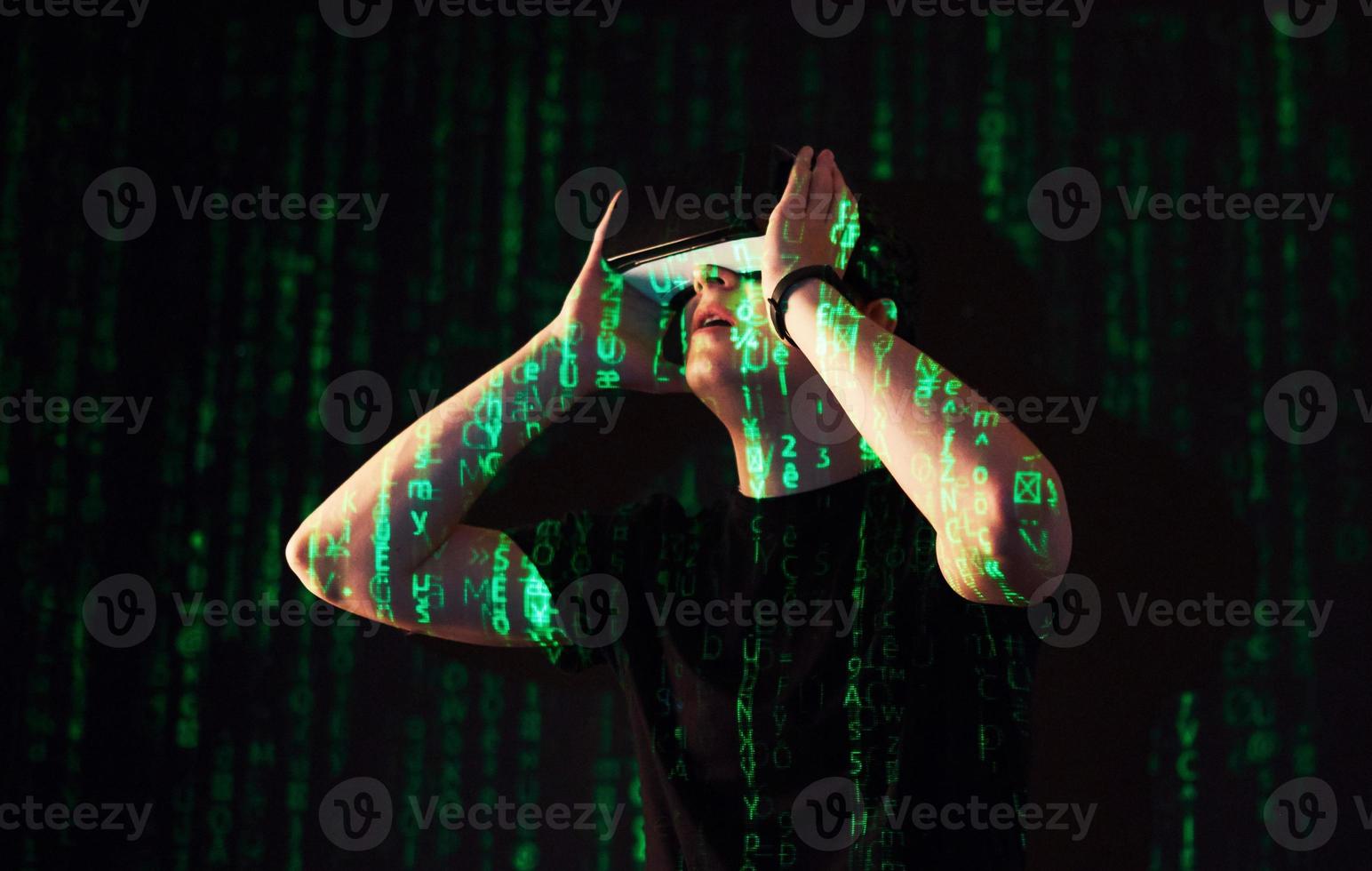 Double exposure of a caucasian man and Virtual reality headset is presumably a gamer or a hacker cracking the code into a secure network or server, with lines of code photo