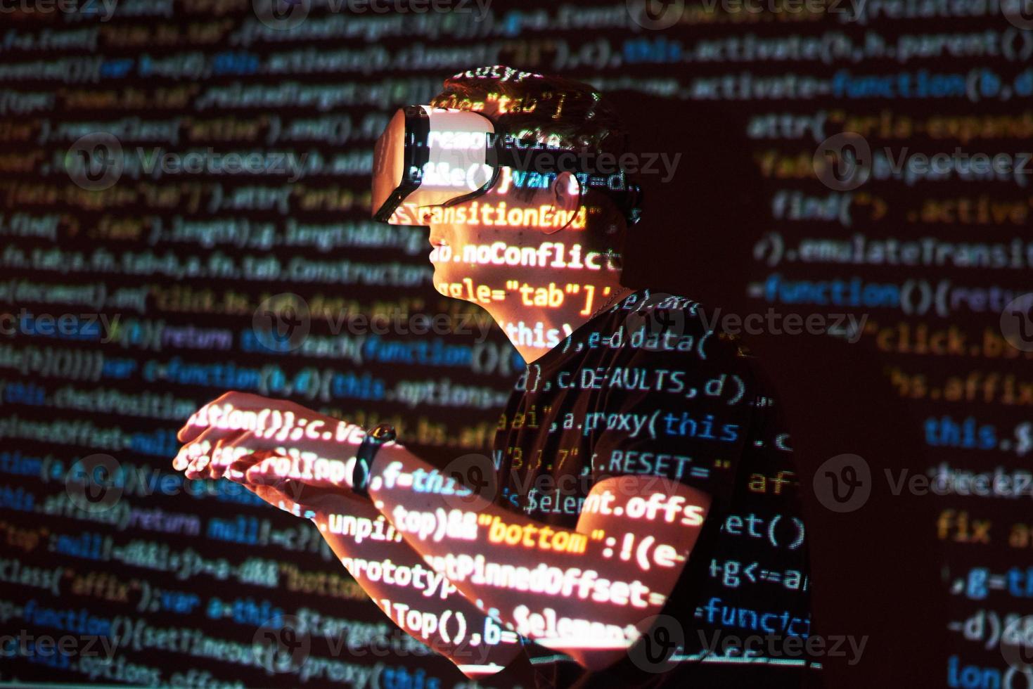 Double exposure of a caucasian man and Virtual reality headset is presumably a gamer or a hacker cracking the code into a secure network or server, with lines of code photo