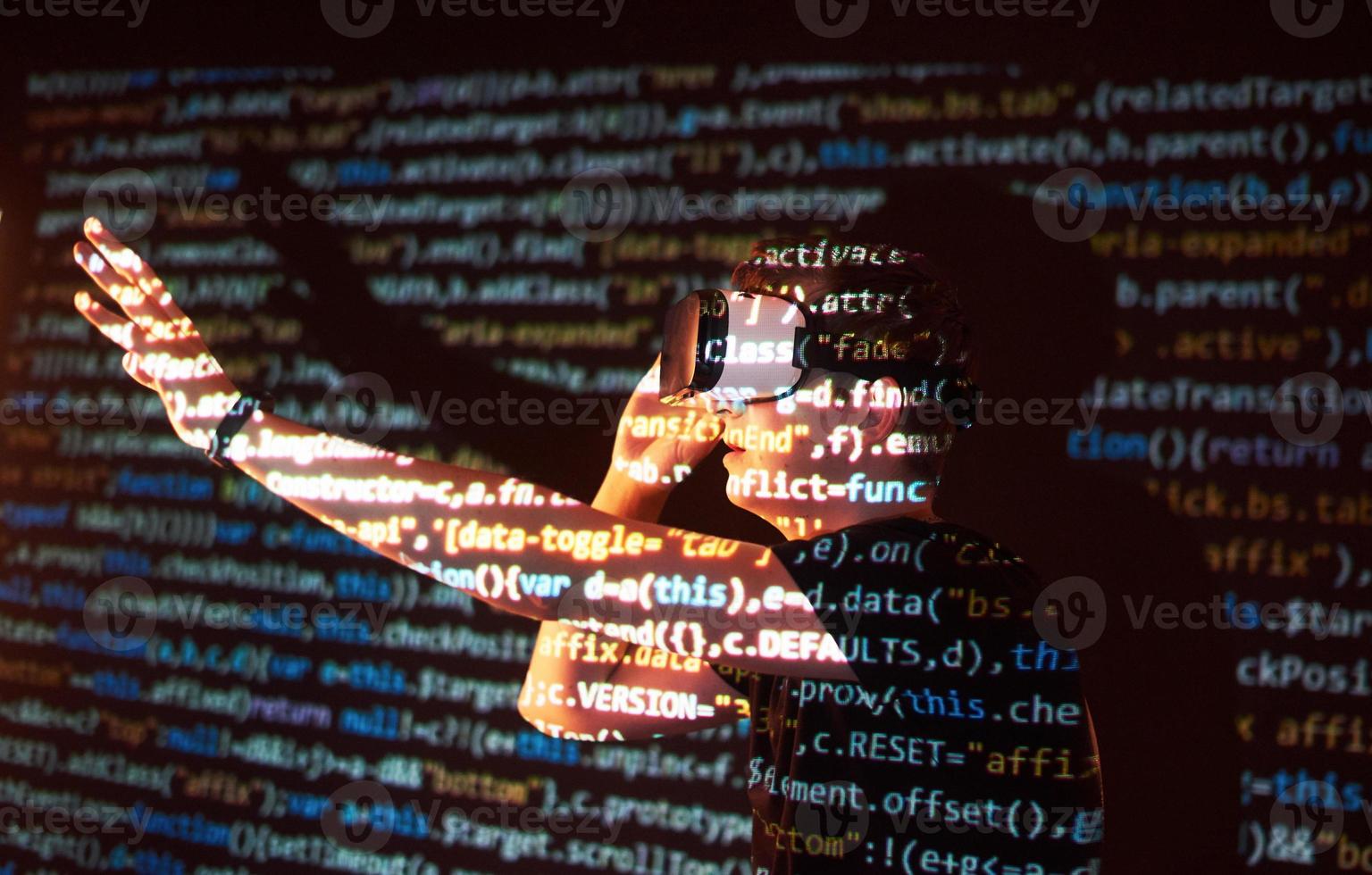 Double exposure of a caucasian man and Virtual reality headset is presumably a gamer or a hacker cracking the code into a secure network or server, with lines of code photo