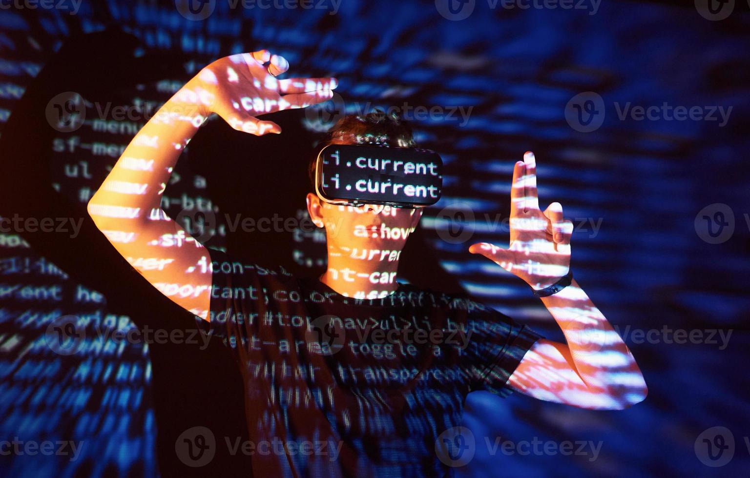 Double exposure of a caucasian man and Virtual reality headset is presumably a gamer or a hacker cracking the code into a secure network or server, with lines of code photo