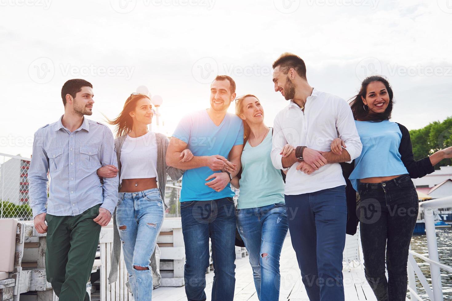 Smiling happy group of friends posing for the camera outdoors on the beach pier photo