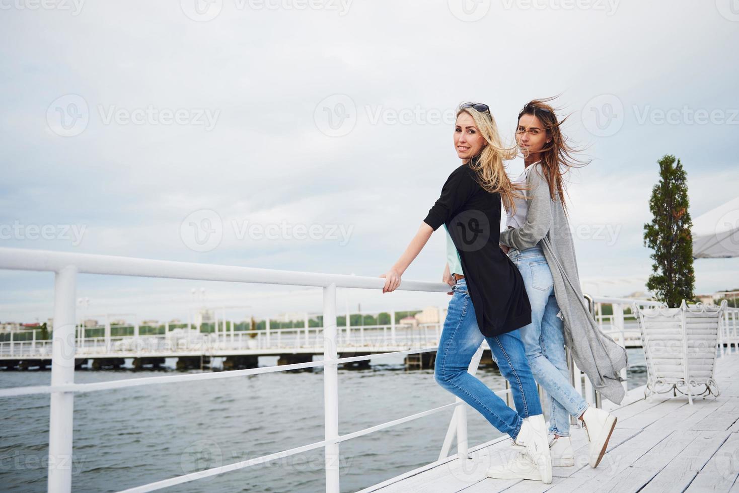 Smiling friends posing for the camera outdoors on the beach pier. photo