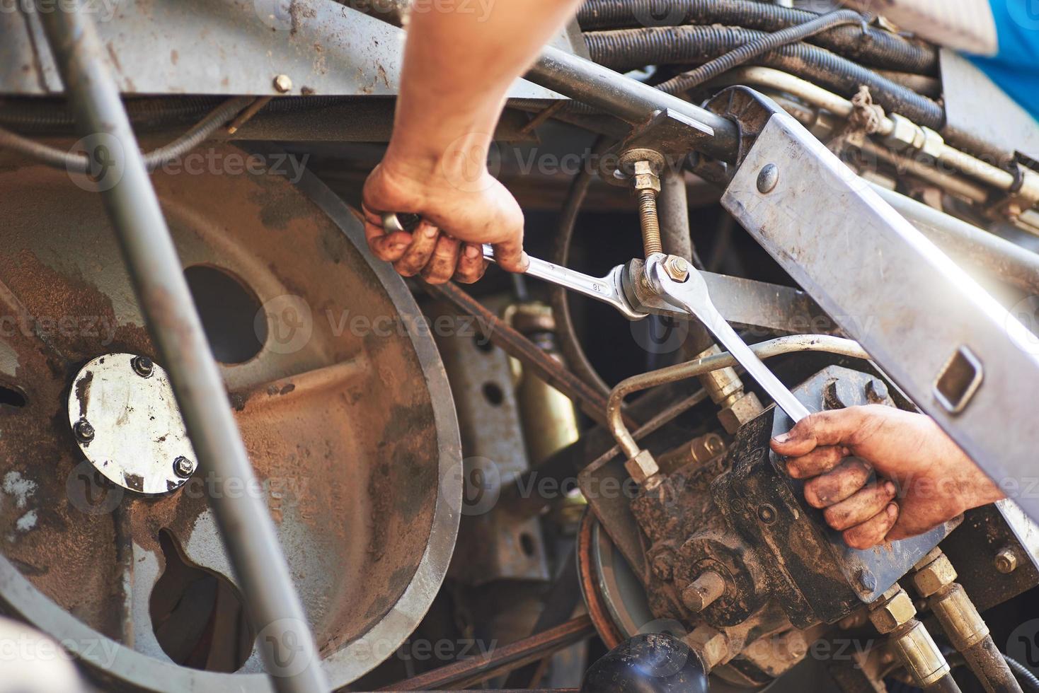 Combine machine service, mechanic repairing motor outdoors photo
