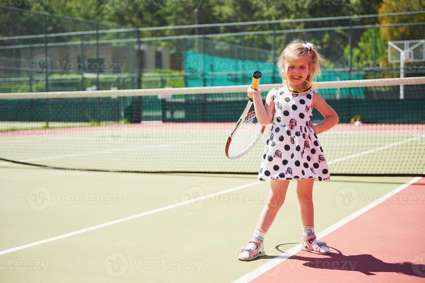 linda niña jugando tenis en la cancha de tenis afuera foto