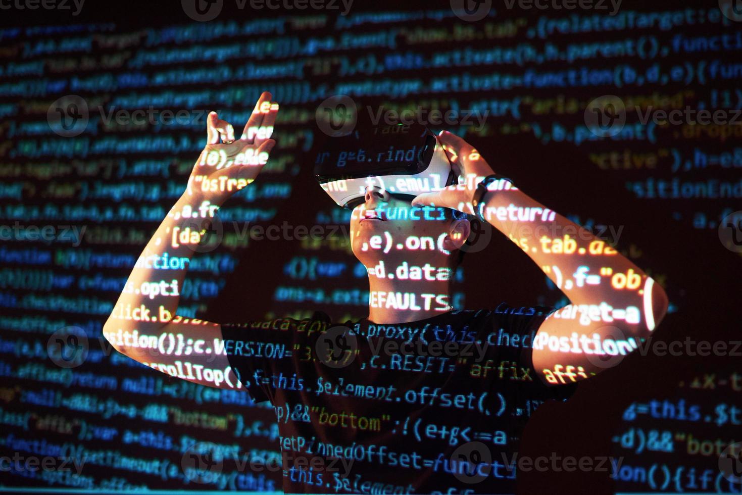 Double exposure of a caucasian man and Virtual reality headset is presumably a gamer or a hacker cracking the code into a secure network or server, with lines of code photo