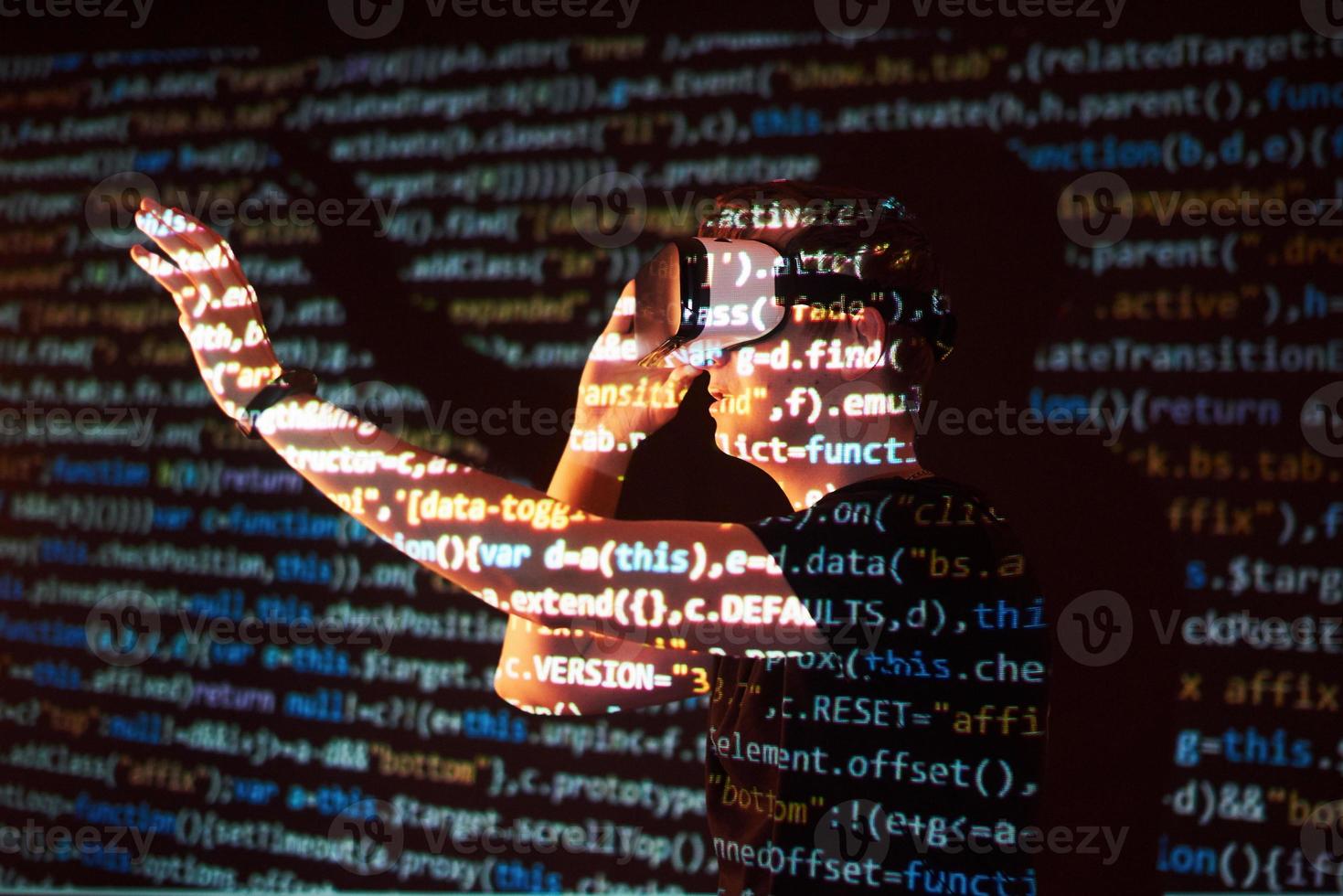 Double exposure of a caucasian man and Virtual reality headset is presumably a gamer or a hacker cracking the code into a secure network or server, with lines of code photo