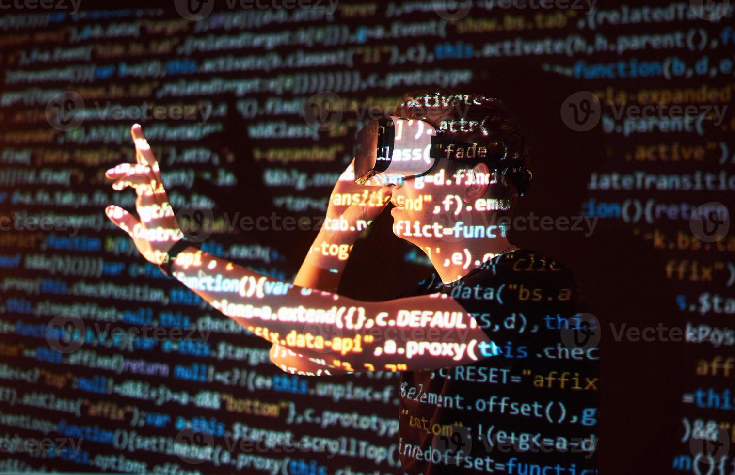 Double exposure of a caucasian man and Virtual reality headset is presumably a gamer or a hacker cracking the code into a secure network or server, with lines of code photo