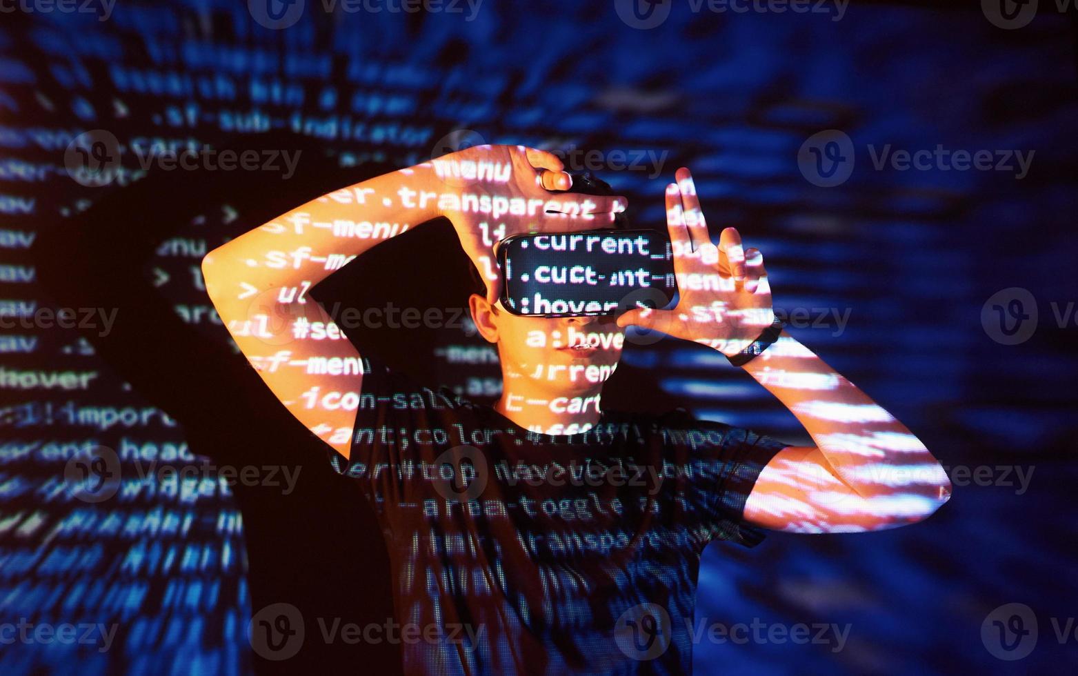 Double exposure of a caucasian man and Virtual reality headset is presumably a gamer or a hacker cracking the code into a secure network or server, with lines of code photo