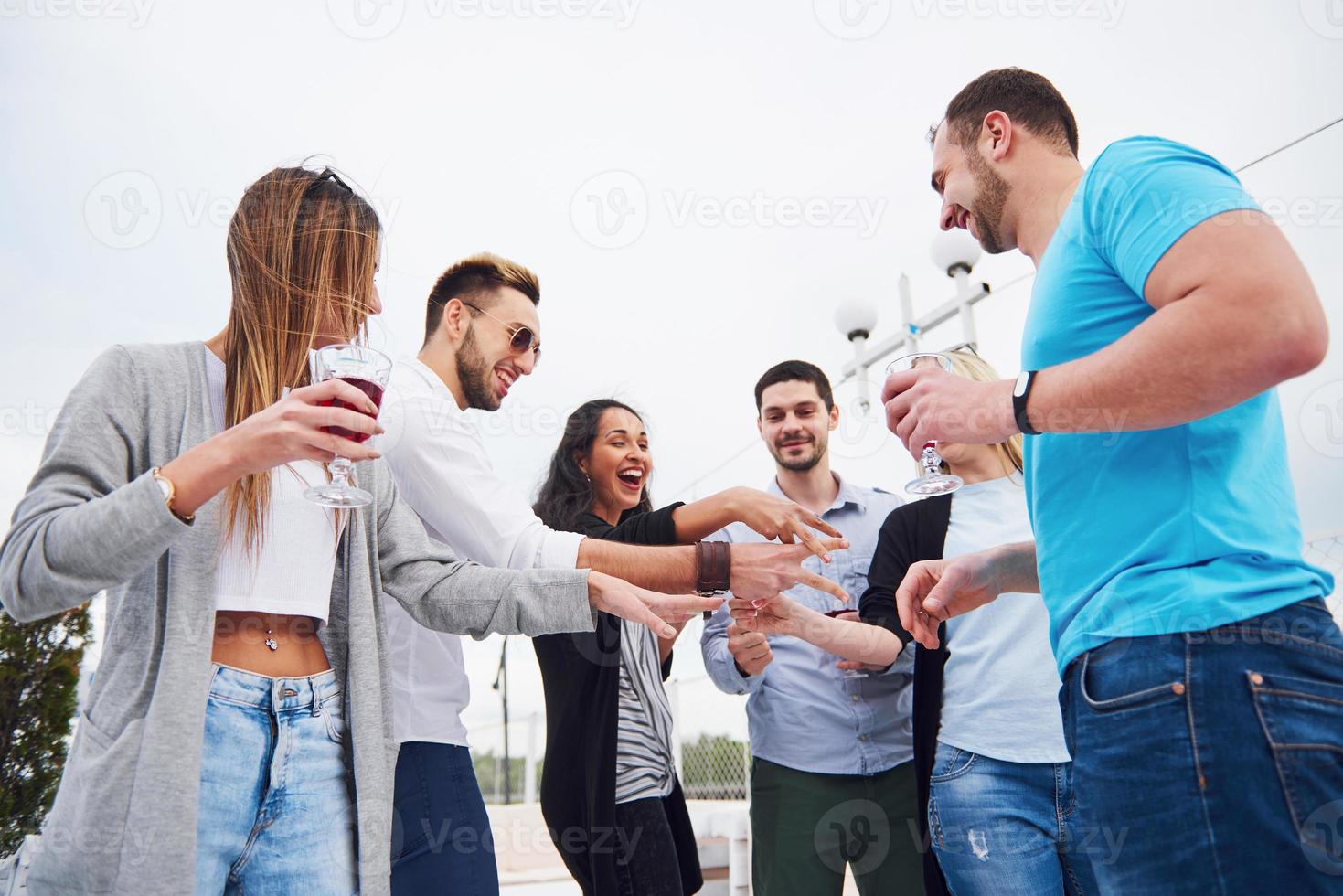 Portrait of a group of young people sitting on the edge of the pier, outdoors in nature. Friends enjoying a game on the lake. photo