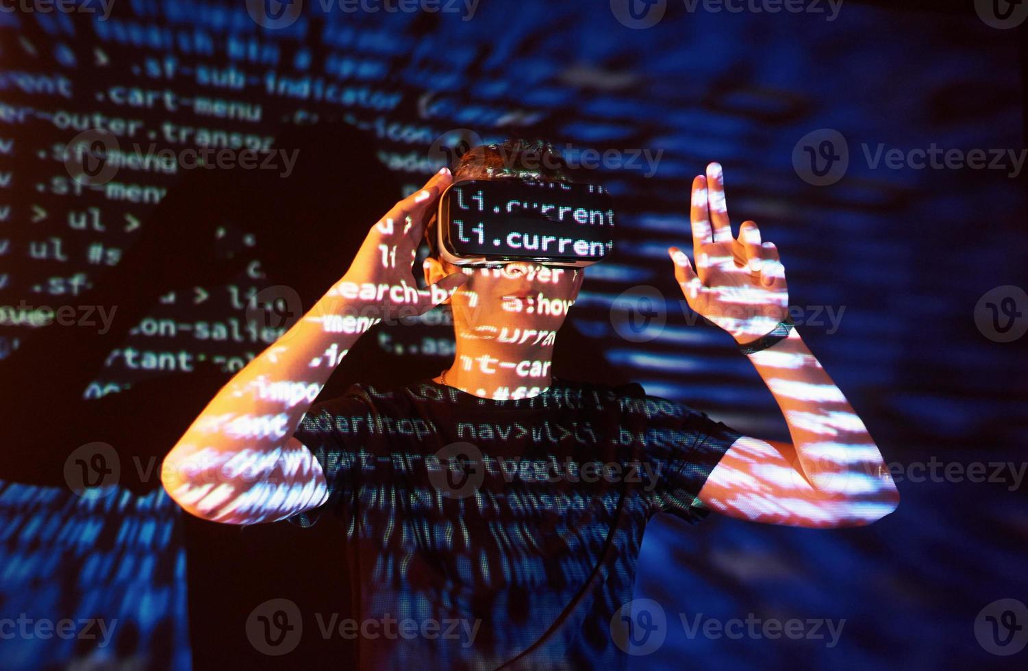 Double exposure of a caucasian man and Virtual reality headset is presumably a gamer or a hacker cracking the code into a secure network or server, with lines of code photo