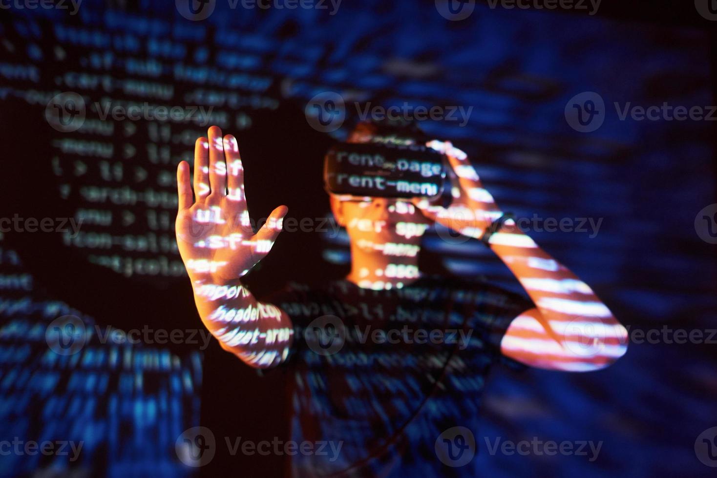 Double exposure of a caucasian man and Virtual reality headset is presumably a gamer or a hacker cracking the code into a secure network or server, with lines of code photo