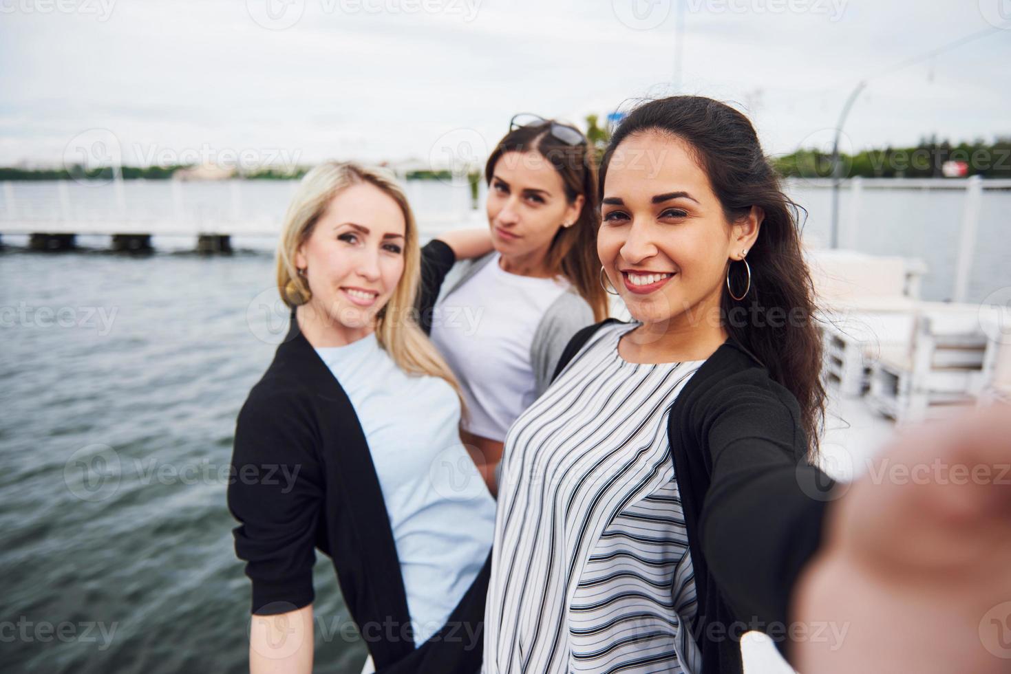 amigos felices en el muelle cerca del agua foto