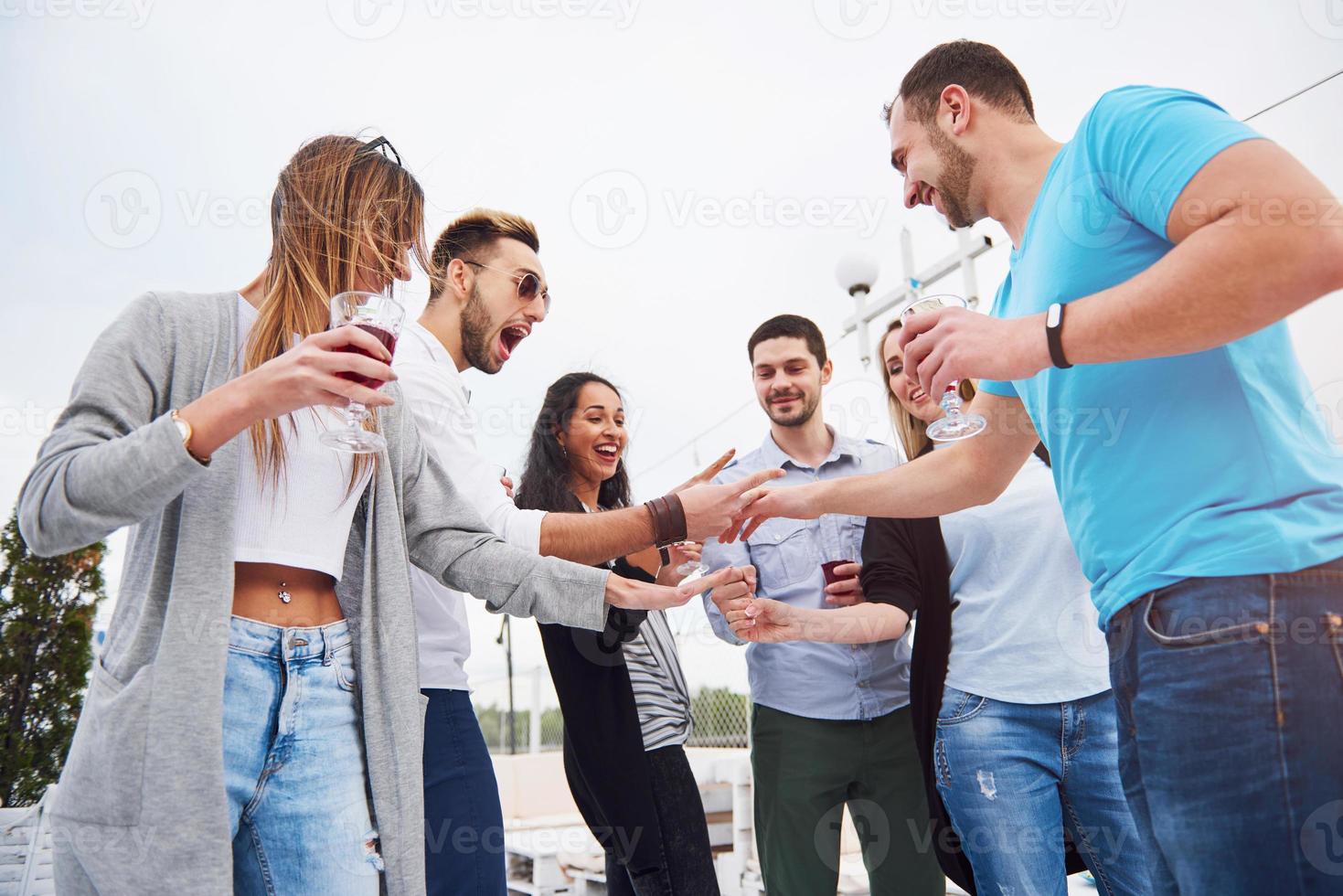 Portrait of a group of young people sitting on the edge of the pier, outdoors in nature. Friends enjoying a game on the lake. photo