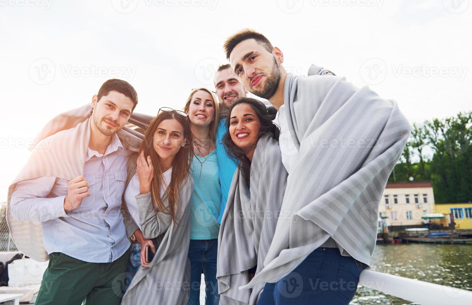 sonriente feliz grupo de amigos posando para la cámara al aire libre en el muelle de la playa foto