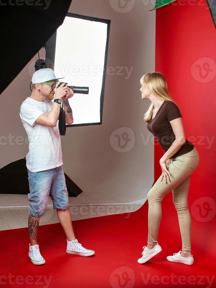 Model posing to photographer in studio on red background. Professional, education, technology concept photo