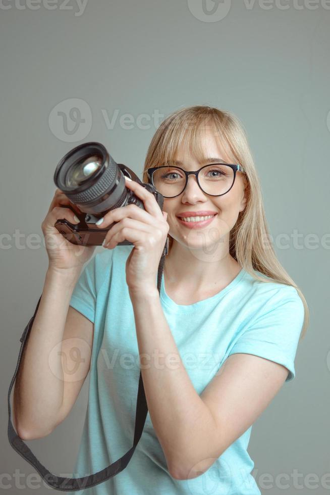 blonde stylish cheerful woman photographer in glasses and holding photo camera. Hobby, work, shooting concept