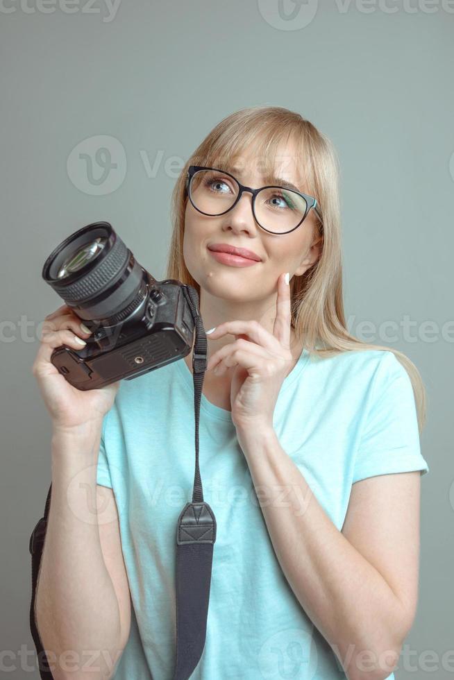 blonde stylish cheerful woman photographer in glasses and holding photo camera. Hobby, work, shooting concept
