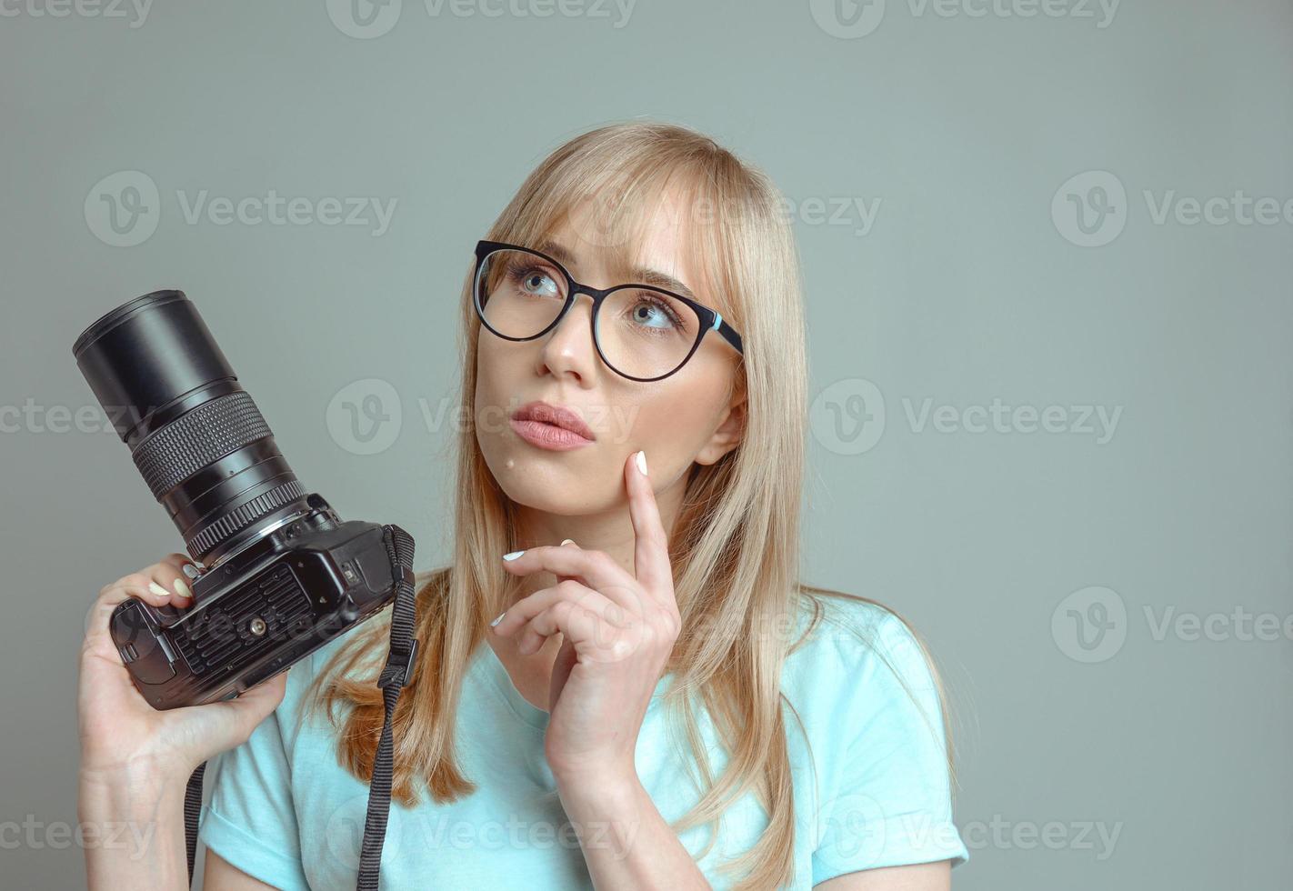 blonde stylish cheerful woman photographer in glasses and holding photo camera. Hobby, work, shooting concept