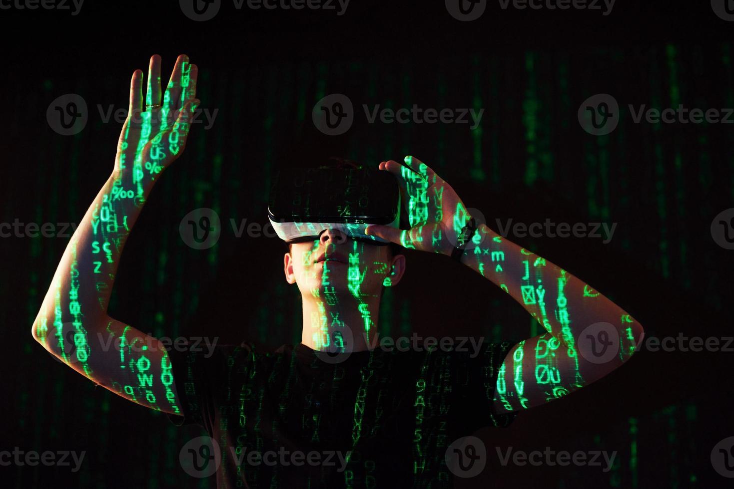 Double exposure of a caucasian man and Virtual reality headset is presumably a gamer or a hacker cracking the code into a secure network or server, with lines of code photo