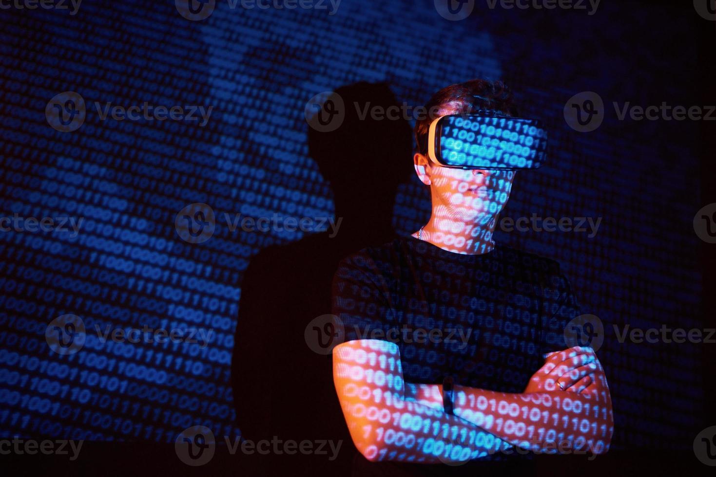 Double exposure of a caucasian man and Virtual reality headset is presumably a gamer or a hacker cracking the code into a secure network or server, with lines of code photo