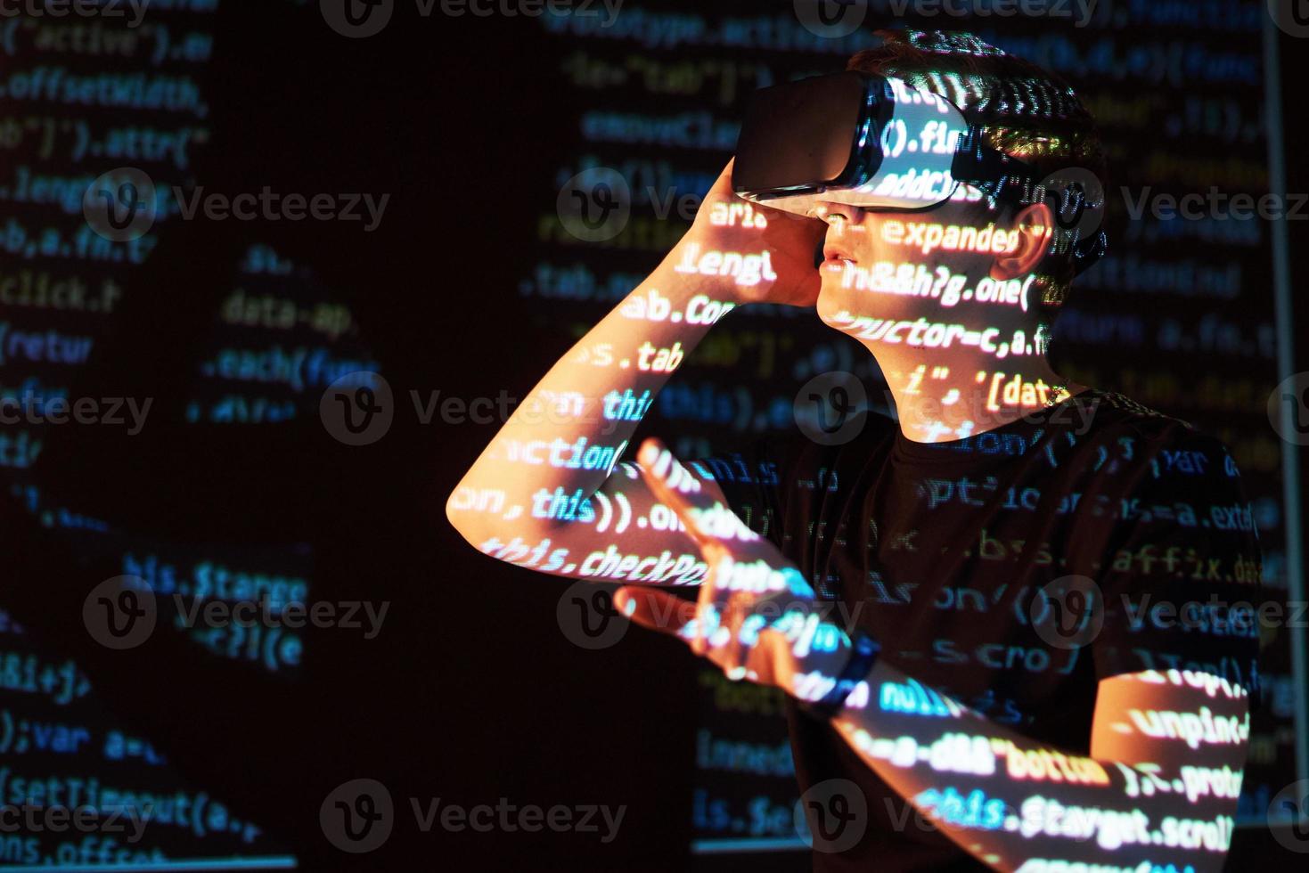 Double exposure of a caucasian man and Virtual reality headset is presumably a gamer or a hacker cracking the code into a secure network or server, with lines of code photo