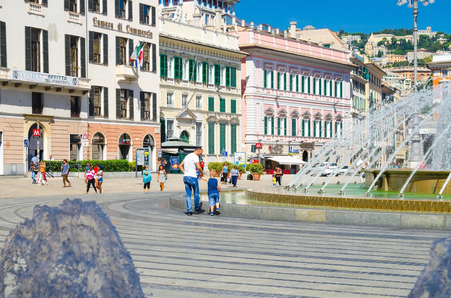 Genoa, Italy, September 11, 2018 father man and son boy are playing walking down the Piazza Raffaele de Ferrari square near fountain in old historical city Genova centre in beautiful summer day photo