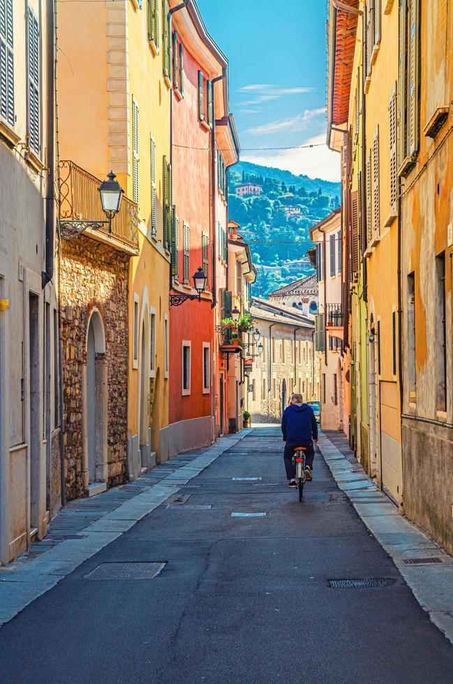 brescia, italia, 11 de septiembre de 2019 calle típica italiana con viejos edificios coloridos con paredes multicolores y hombre en bicicleta foto