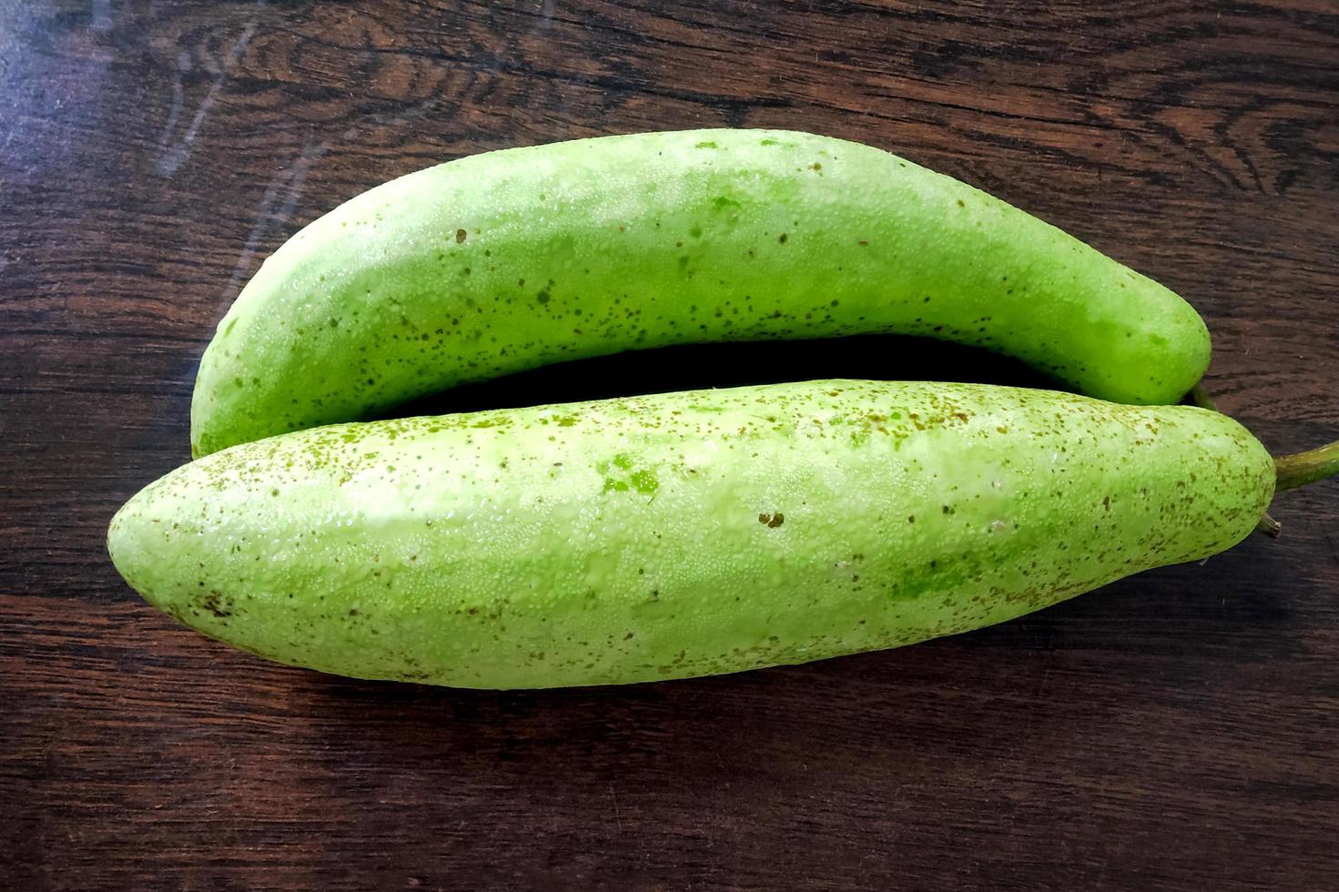 dos calabazas verdes colocadas sobre una mesa de madera foto