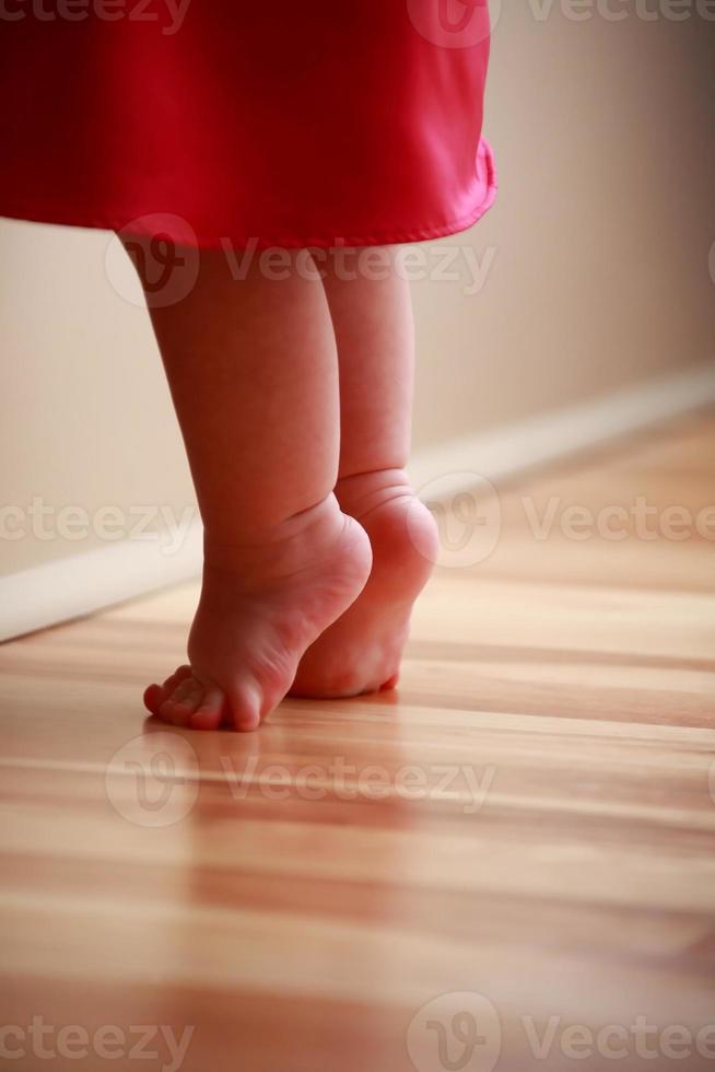 pies de bebé estirándose en un piso de madera foto