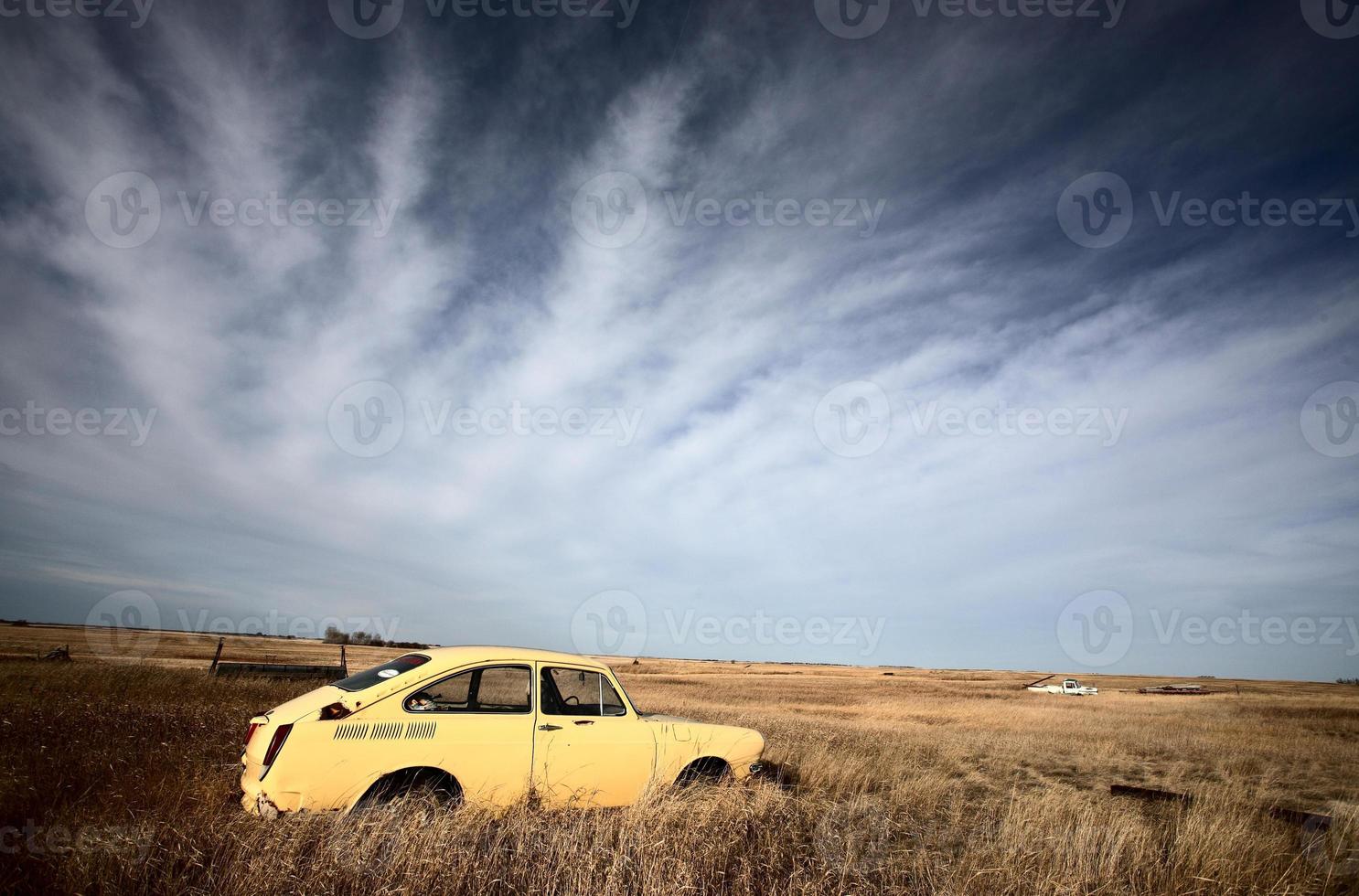 Discardfed yellow foreign car in vacant lot photo