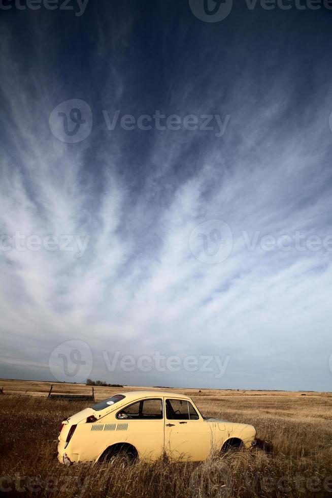 Wispy clouds over abandoned foreign made car photo