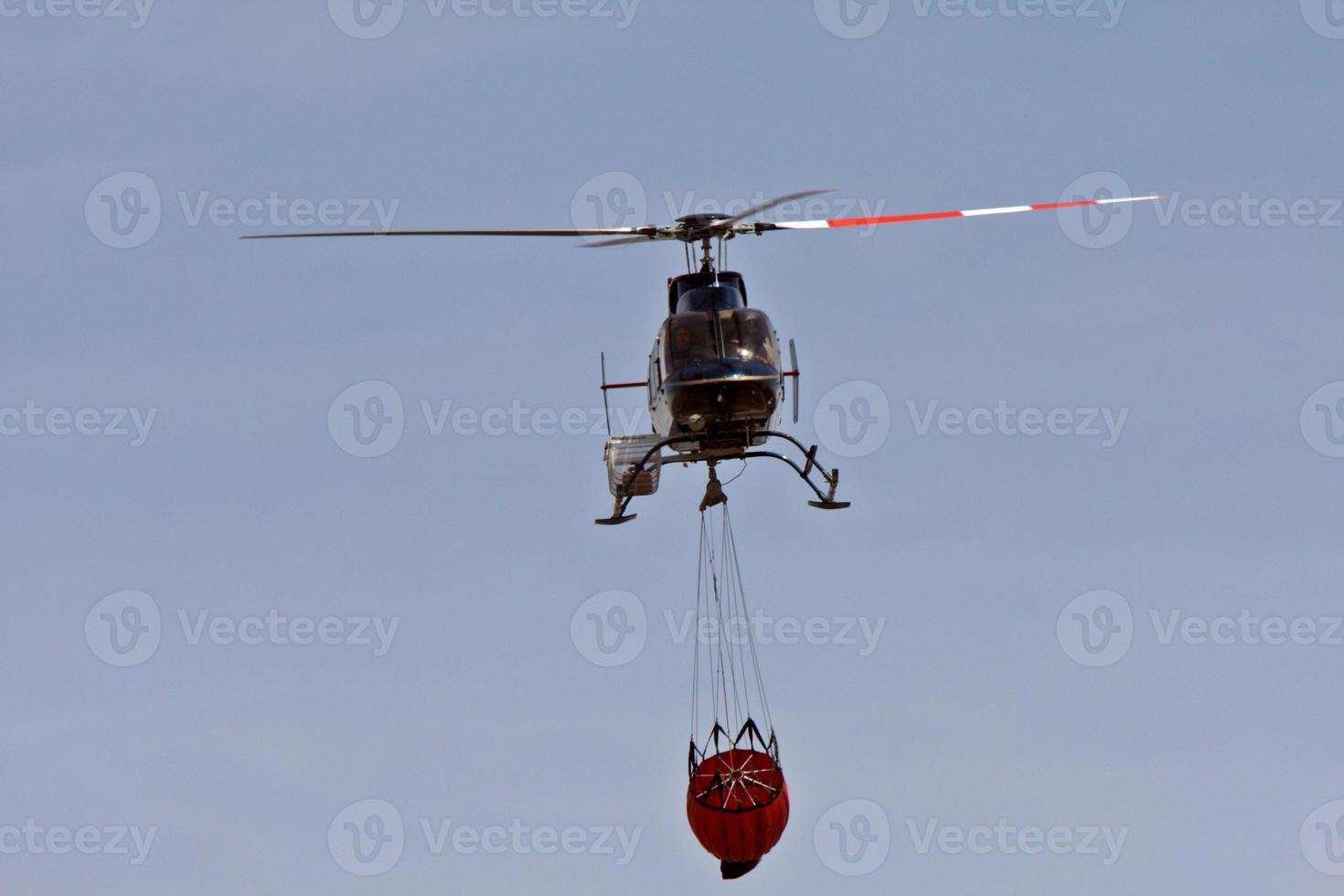 Helicóptero llevando agua al fuego. foto