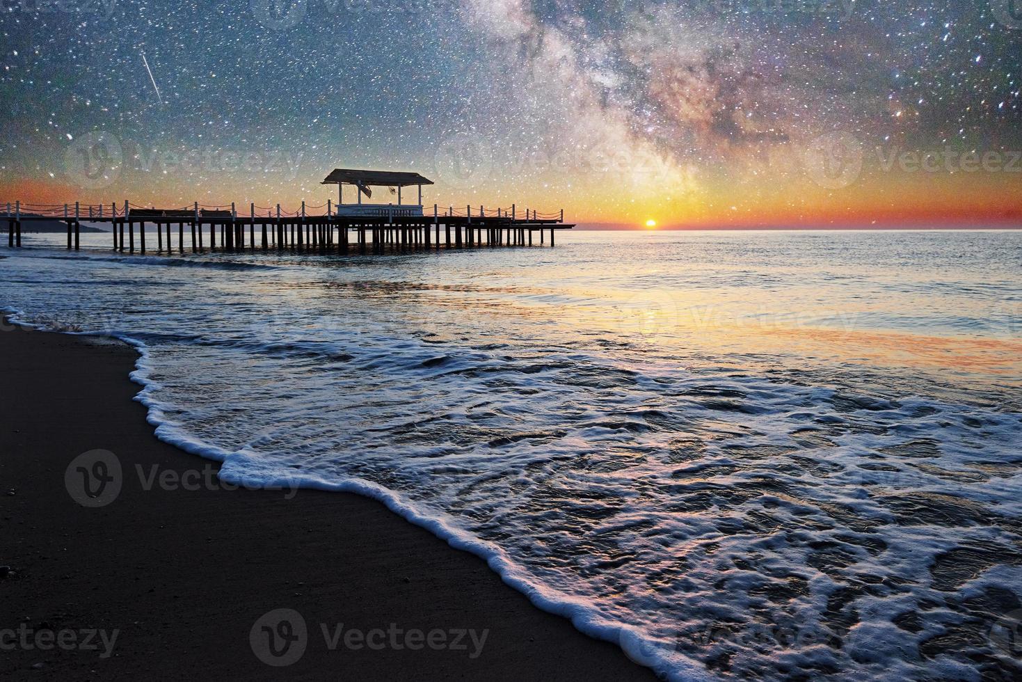 fantástico cielo estrellado y la vía láctea al muelle en el mar, acostumbrado al mar de fondo natural. noche romantica. foto