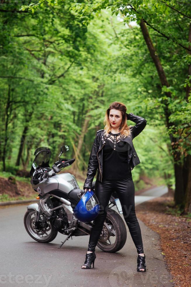 una atractiva chica sexy en una moto deportiva posando afuera foto