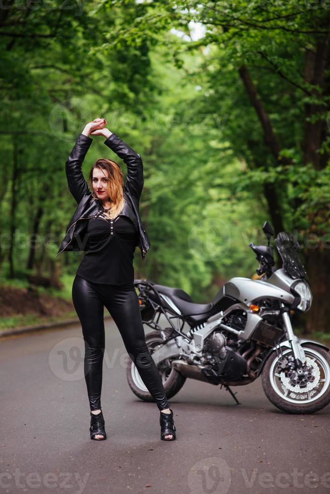 An attractive sexy girl on a sports motorbike posing outside photo