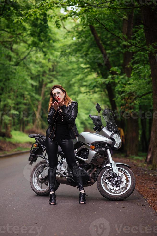 An attractive sexy girl on a sports motorbike posing outside photo