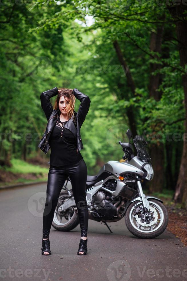 An attractive sexy girl on a sports motorbike posing outside photo