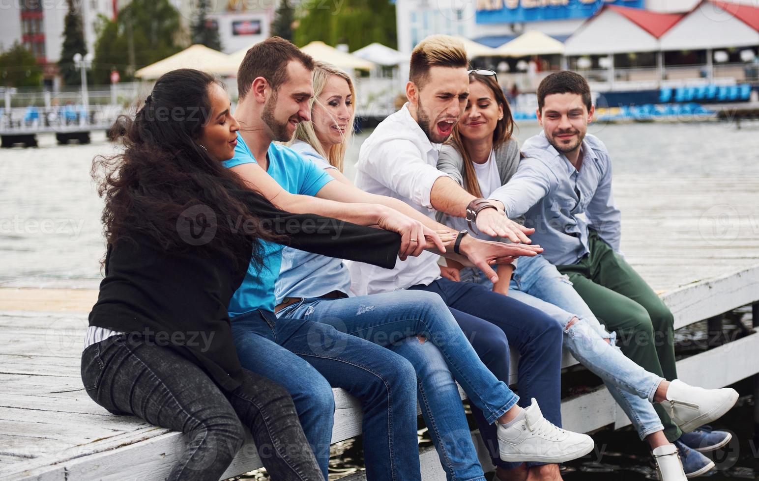 Group of happy young friends on the pier, pleasure in playing creates emotional life photo