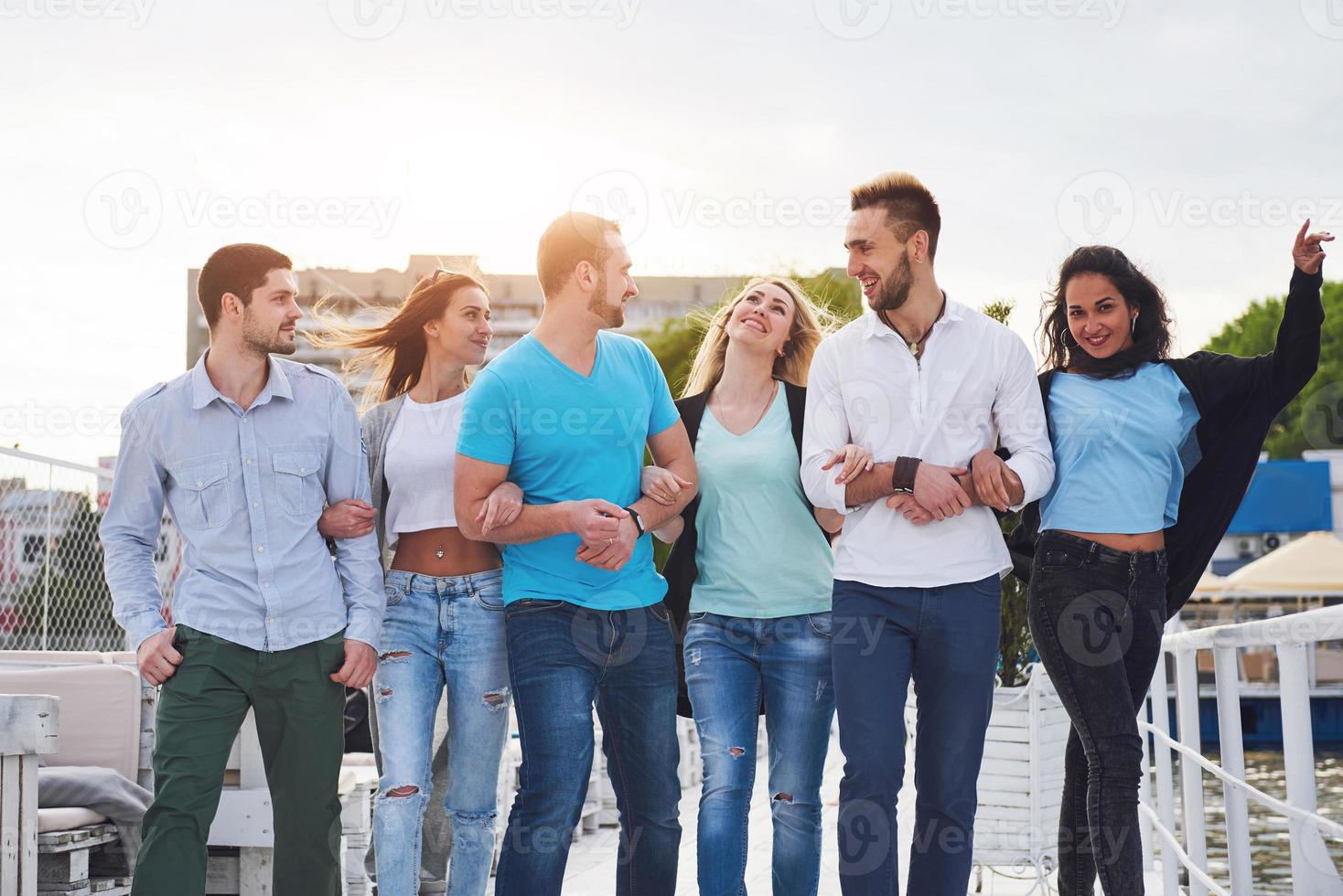 retrato de un grupo de jóvenes sentados al borde del muelle, al aire libre en la naturaleza. amigos disfrutando de un juego en el lago. foto