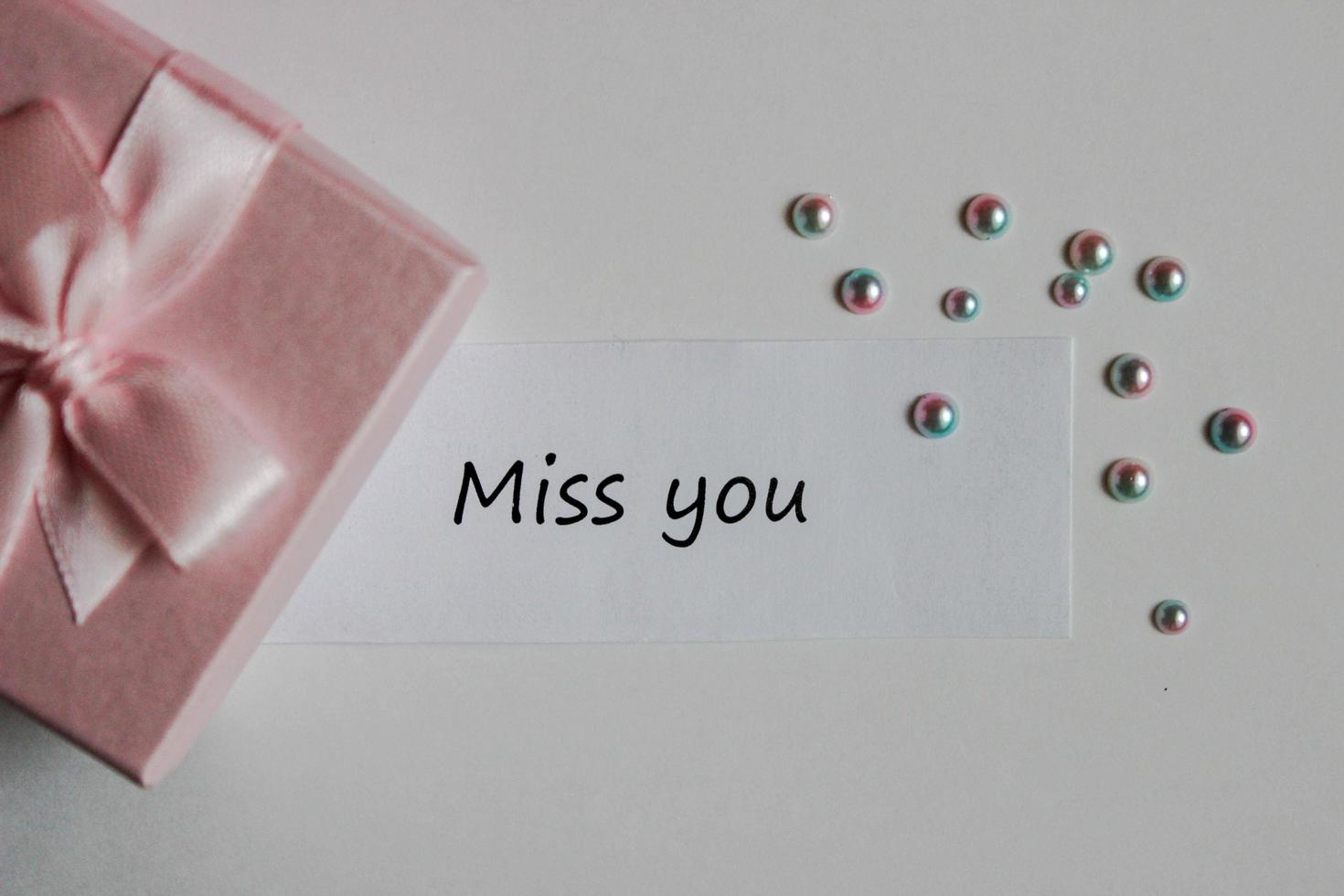 Note miss you with gift box and decorative pearls on white background photo