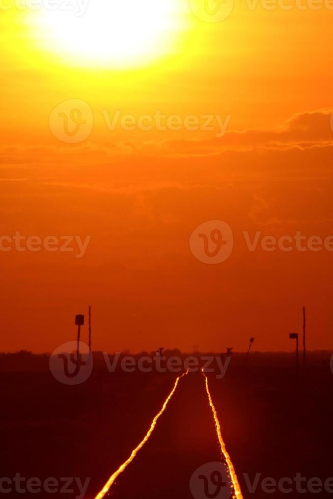 Setting sun shining on railroad tracks photo