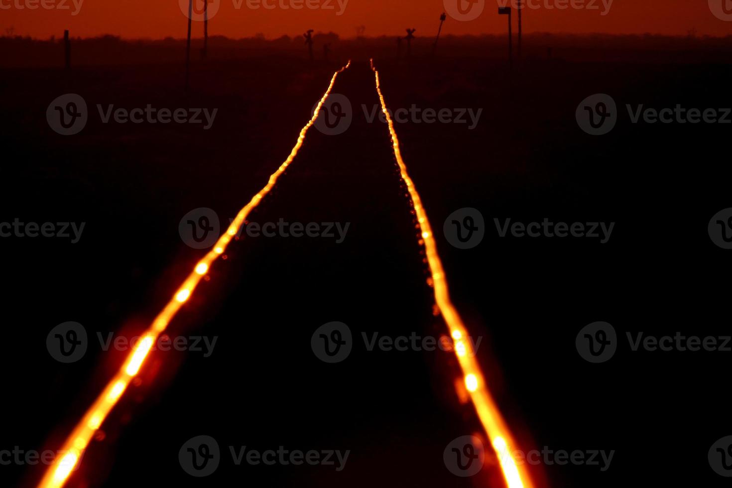 Setting sun shining on railroad tracks photo